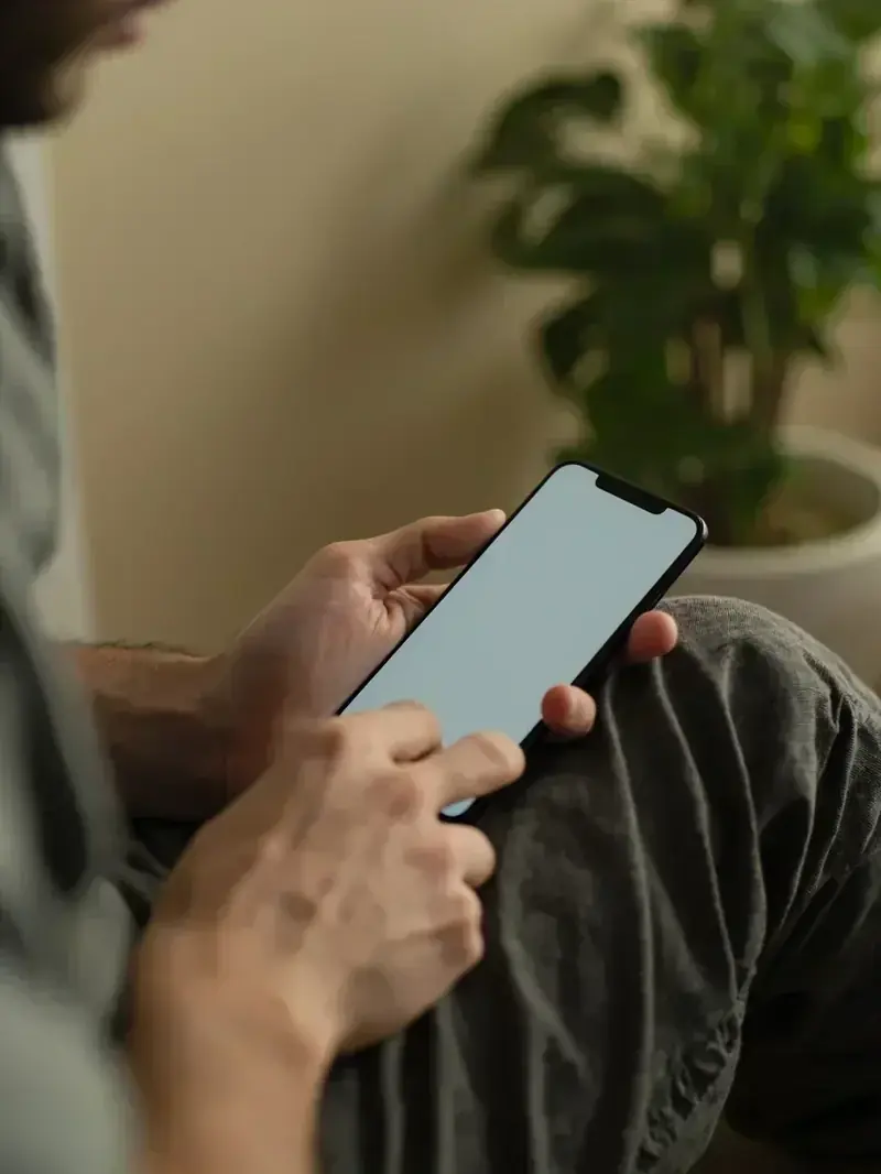 A phone on a seated adult's lap with an unreadable pale screen