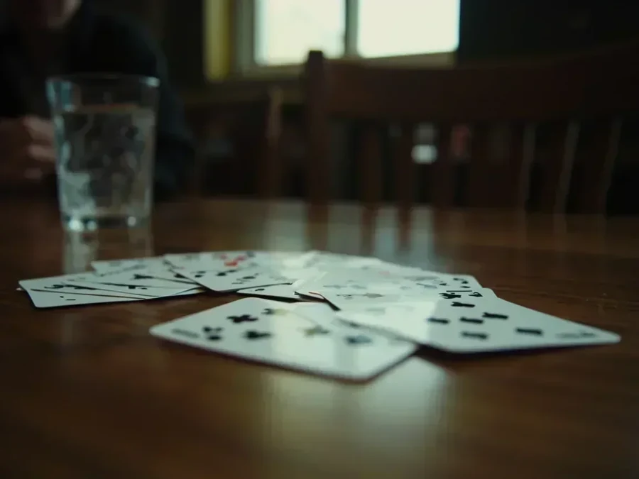 A seated view of a discard pile on oak with a glass of water beyond