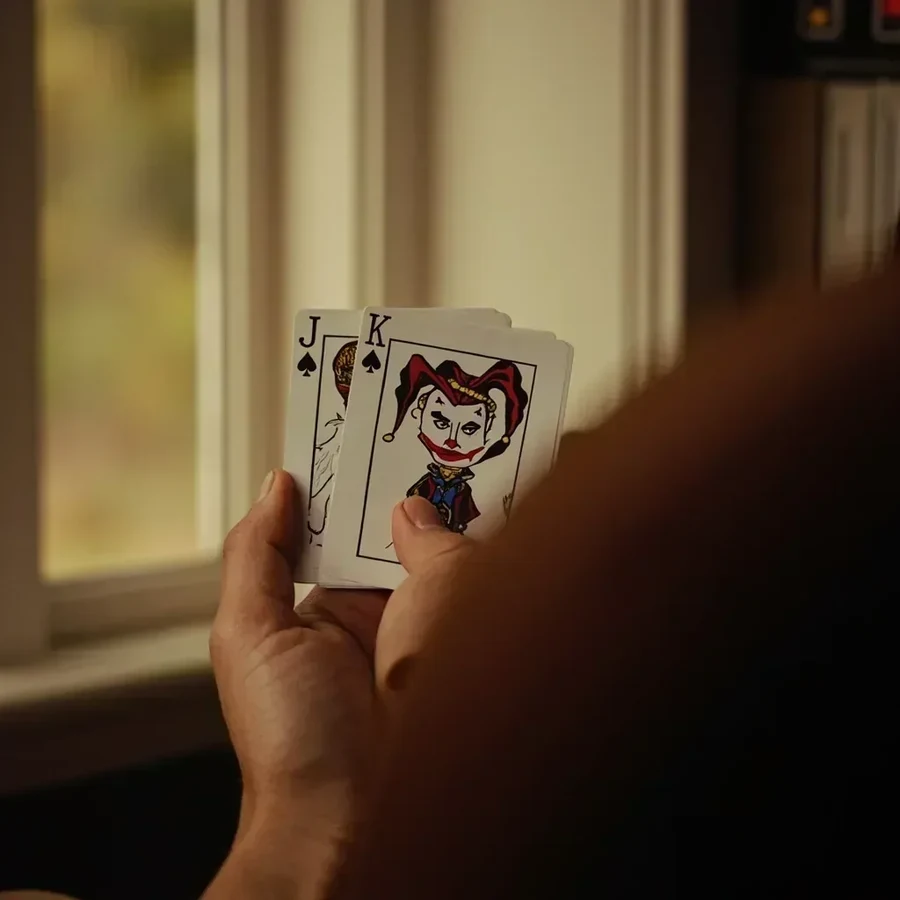 Two pictorial jokers tucked behind a small fan of suited cards